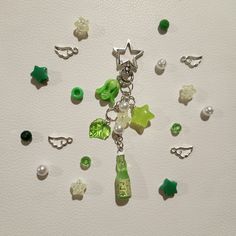 a bunch of charms that are on top of a white surface with green and white beads