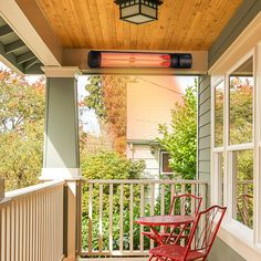 a red rocking chair sitting on top of a wooden porch next to a light fixture