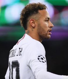 a close up of a soccer player wearing a white shirt and holding a ball in his hand