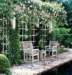 an outdoor dining area with tables and chairs next to a pool surrounded by greenery