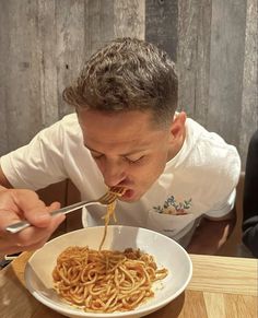 a man is eating noodles from a white bowl