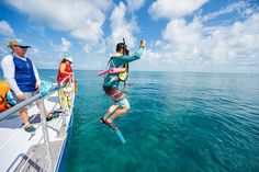 people on a boat in the water with one person holding onto a life preserver