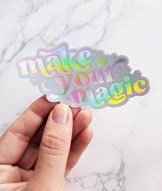 someone holding up a sticker that says make your magic