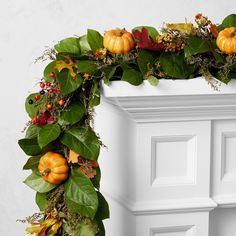 a wreath with pumpkins and greenery on it