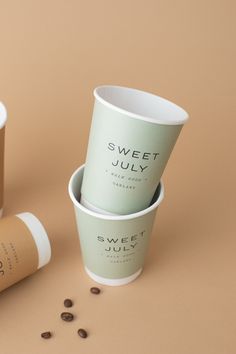 three coffee cups sitting next to each other on top of a brown table with coffee beans