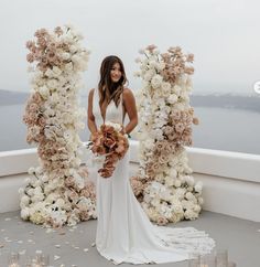 a woman in a white dress standing next to flowers and candles on top of a roof