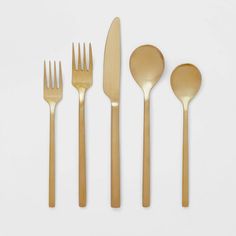 gold flatware is laid out on a white surface