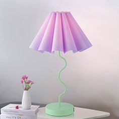 a pink and green lamp sitting on top of a table next to a white box