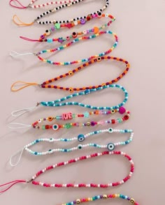 several bracelets are lined up on a table with beads and charms hanging from them