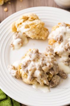 a white plate topped with biscuits covered in gravy next to a cup of coffee