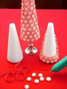 the table is covered with white vases and other items to decorate it for someone's holiday party