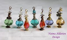 nine different colored glass bead charms in various shapes and sizes on a white surface