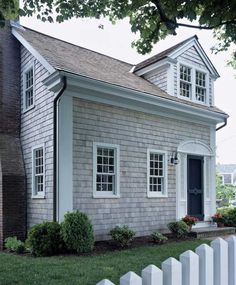 a white picket fence in front of a gray house