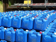 many blue plastic jugs are lined up on the ground