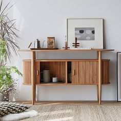 a living room with white walls and wooden furniture on the floor next to potted plants