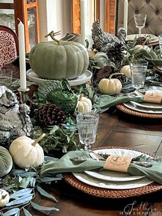 a dining room table set for thanksgiving dinner with green and white decorations on the place settings