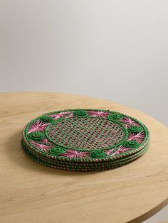 a green and pink plate sitting on top of a wooden table