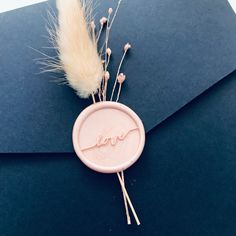 a pink wax stamp with the word love on it sits next to some dried flowers