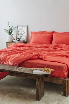 a bed with an orange comforter on top of it next to a wooden bench