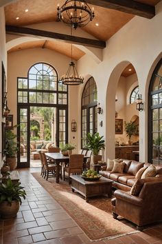 a living room filled with lots of furniture next to large windows and potted plants