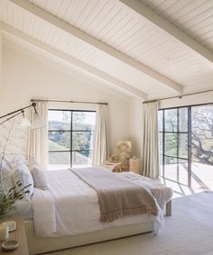 a bedroom with a large bed sitting next to two windows on each side of the room