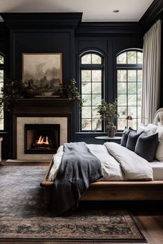 a bedroom with black walls, a fireplace and a large bed in the middle of it