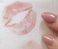 a woman's hand holding onto a piece of paper with lipstick drawn on it