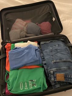 an open suitcase filled with clothes on top of a bed