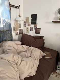 an unmade bed in a room with pictures on the wall and a lamp hanging above it