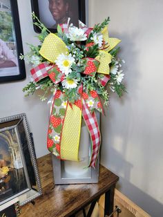 a vase filled with flowers sitting on top of a table next to a framed photo