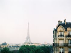 the eiffel tower towering over the city of paris, seen from an apartment building