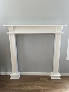 a white fireplace mantel sitting on top of a hard wood floor next to a gray wall