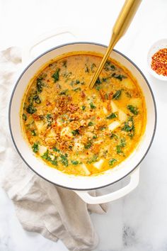 a white bowl filled with soup next to a gold spoon on top of a table