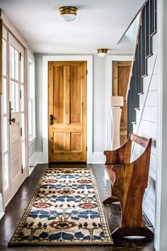 an entryway with a rug and wooden staircase leading to the second floor, along with two doors