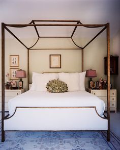 a four poster bed with white linens and pillows on top of it in a bedroom