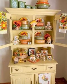 a yellow china cabinet with dishes and cups on it