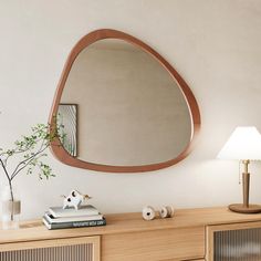 a wooden dresser topped with a mirror next to a lamp