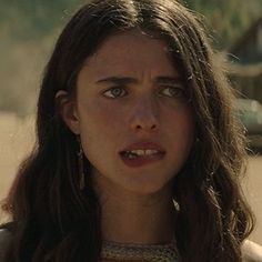 a close up of a person with long hair and wearing earrings looking at the camera