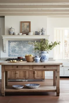 a table with bowls and plates on it in a room that has white walls and wood floors