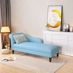 a blue chaise lounge sitting on top of a wooden floor next to a window