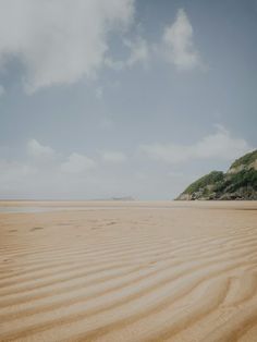 a sandy beach with hills in the distance