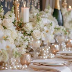 the table is set with white flowers and pearls