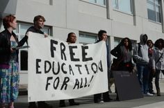 a group of people holding a free education for all sign in front of a building