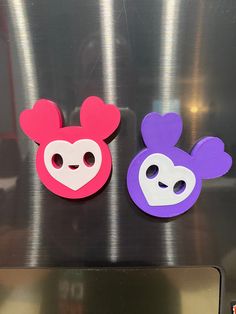 two mickey and minnie mouse magnets sitting on top of a refrigerator