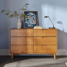 a wooden dresser sitting next to a wall with a painting on it's side