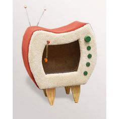 a tooth shaped oven with green beads on it's teeth and legs, sitting on top of a white surface