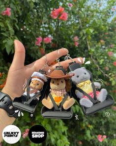 a hand holding three small stuffed animals on top of it's fingers and wearing hats