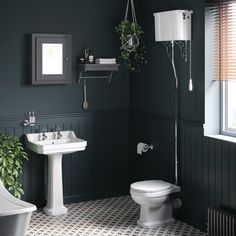 a white toilet sitting next to a bathroom sink under a window in a green room