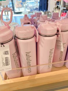 pink water bottles are on display in a store