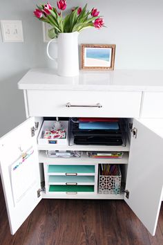 a white cabinet with drawers and some flowers